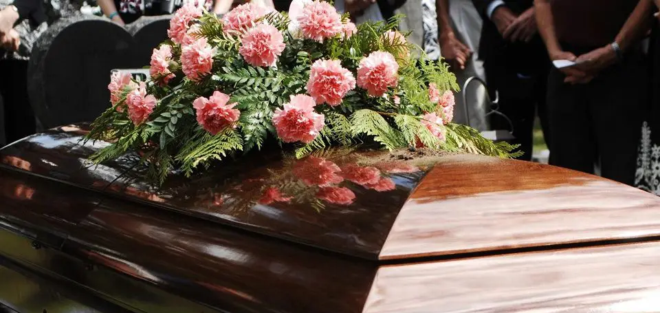 A wooden casket with pink flowers on top of it.